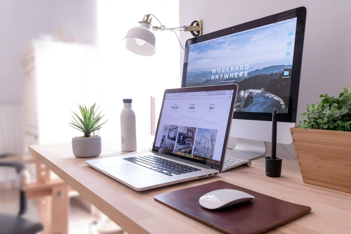 A designer's desk with laptop and desktop screens